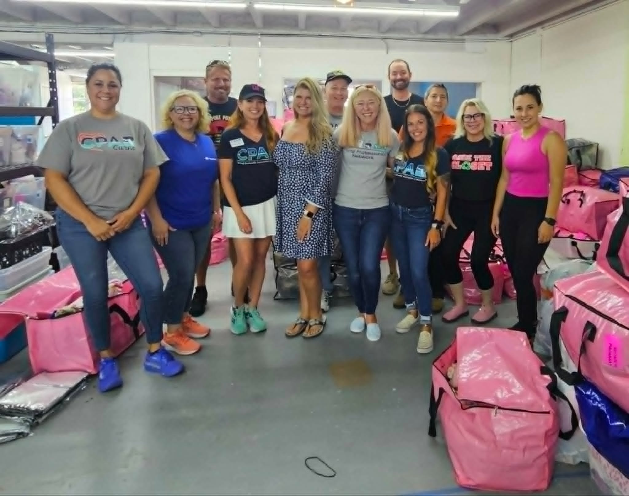 Volunteers posing in warehouse with pink donation bins
